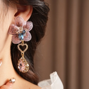 Close-up of vintage pink embroidered flower earring with crystal drop on model