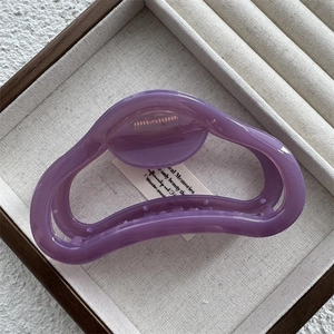 Dettaglio di una molletta per capelli viola traslucida in una scatola di gioielli in lino