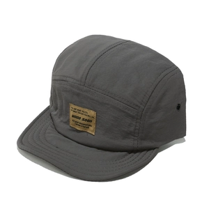 Close-up of the brown brand patch and textured nylon fabric on a 5-panel camper hat