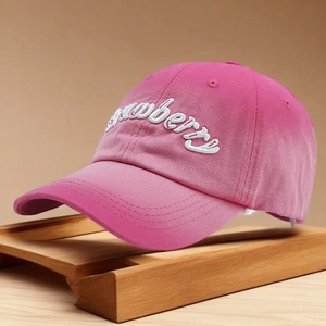 Pink washed cotton baseball cap with white Strawberry embroidery on wooden stand