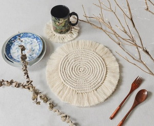 Top-down view of woven macrame placemats with fringe in different sizes and neutral tones