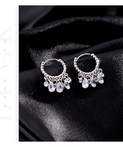 Detail of silver drop earrings featuring shimmering crystals on a black silk background