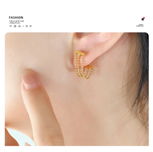 Close-up of gold-plated triple strand bead tassel earrings worn on a female model