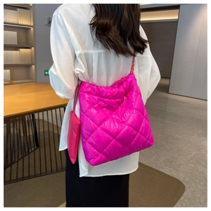 Modella che indossa una borsa a spalla in nylon trapuntato magenta con catena oro