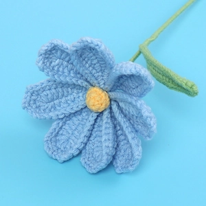 Macro shot of handmade crochet Cosmos flower with sky blue petals and yellow stamen