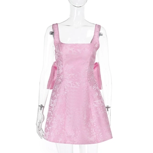 Gros plan sur le tissu jacquard rose avec texture florale 3D et nœud latéral sur la robe