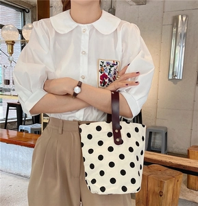 Detailed embroidery on white shirt pocket paired with vintage polka dot canvas bag