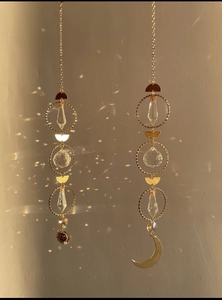 Detail of crystal suncatcher with golden sun and moon pendants creating rainbow reflections
