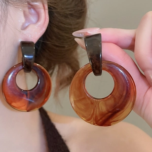 Close-up of geometric resin hoop earrings with amber tortoiseshell pattern on model