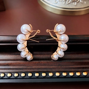 Elegant gold curved stud earrings with five gradient pearls on vintage wood frame