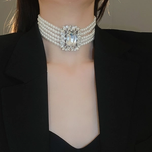 Close-up of five-strand pearl choker with large square rhinestone pendant on a model