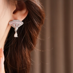 Close-up of shell fan earring with pearls and teardrop diamonds worn on the ear