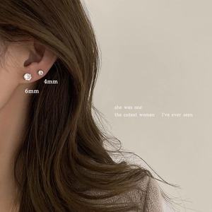 Detail view of 4mm and 6mm sparkling zircon silver stud earrings on a female ear