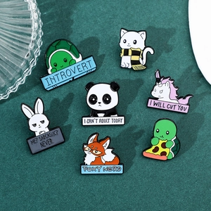 Detailed view of seven colorful enamel animal brooches with fun quotes on green fabric