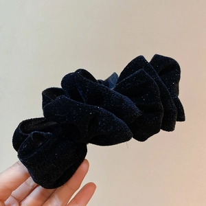 Vue détaillée d'un chouchou fleur en velours noir avec des paillettes scintillantes