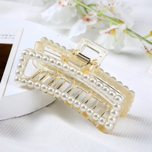 Detailed close-up of a clear pearl-encrusted hair claw clip with floral background decor