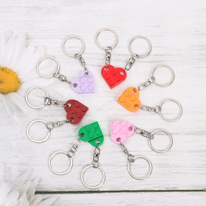 Creative brick heart keychains for couples in multiple colors on a white wooden background