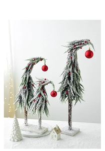 Three creative snowy flocked Christmas trees with red ornaments on wooden bases