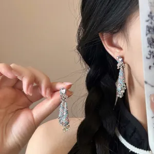Macro detail of silver tassel earrings with blue and pink gems and teardrop stones