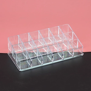 Close-up of clear acrylic lipstick organizer with multiple grid slots on a two-tone background