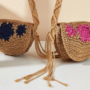 Close-up of handmade straw shoulder bag featuring navy and rose red crochet flowers