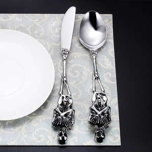 Close-up of stainless steel skull handle knife and spoon set on a vintage mat
