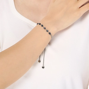 Silver adjustable evil eye bracelet with heart charms worn on a woman's wrist