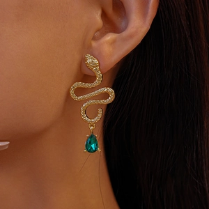 Detailed close-up of golden snake drop earring featuring a green pear-cut gemstone