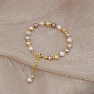 Detail of adjustable gold slider clasp and pastel pearls on elegant silk fabric