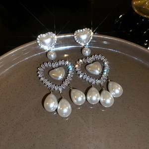 Dettaglio di orecchini a cuore con perle e strass su un vassoio di ceramica