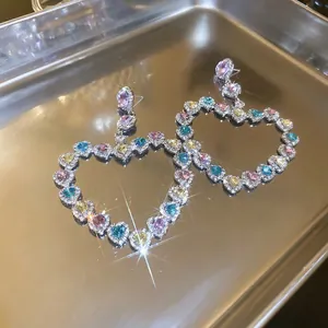 Boucles d'oreilles cœur évidées avec cristaux colorés sur plateau argenté