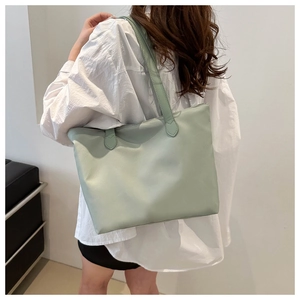 Light green nylon tote bag worn by a model showcasing the casual shoulder strap design