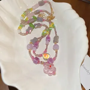 Colorful glass flower beaded necklace with pastel beads and gold clasp on white plate
