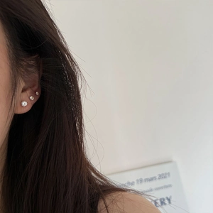 Close-up of three sparkling zircon studs in descending sizes on ear with silver finish