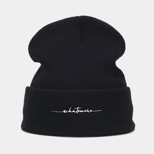 Detail showing white whatever embroidery on a black ribbed knit beanie cap for women
