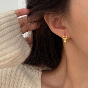 Detail of 925 sterling silver knotted hoop earrings worn by a model in a side view close-up