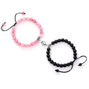 Detail of magnetic heart clasp connecting pink and black beaded bracelets on woven cords
