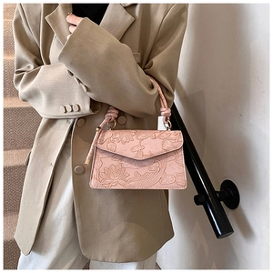 Detail of pink faux leather bag featuring embossed lotus and koi fish patterns