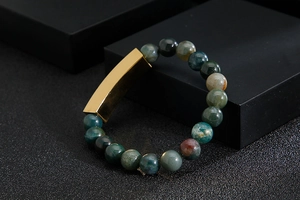 Detailed close-up of dark green agate beads and a polished gold-plated metal bar bracelet