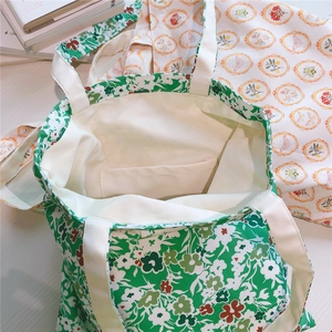 Detail view of cotton floral tote bags showing inner pocket and reinforced canvas stitching