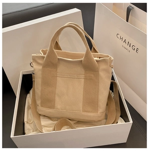 Beige canvas tote bag presented in a white gift box with adjustable shoulder strap
