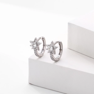 Detailed view of silver star earrings with cubic zirconia on a white display stand