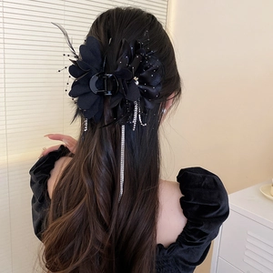 Detail einer schwarzen Blumen-Haarklammer mit Strass-Quasten auf langem Haar