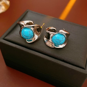 Detailed shot of silver geometric earrings with turquoise stones on black jewelry box