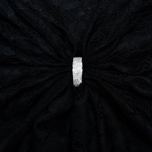 Close-up of a silver ring with pavé-set crystals on elegant black lace fabric