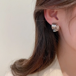 Close-up of geometric layered silver earrings with metallic finish worn by a model