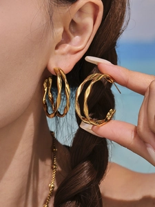 Détail de boucles d'oreilles C torsadées dorées à double couche montrant un fini brillant