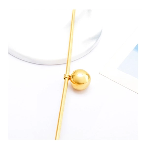 Macro view of golden snake chain necklace with a polished spherical metal pendant