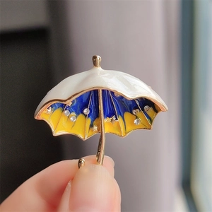 Detailed close-up of a star umbrella brooch with blue and yellow enamel and crystals