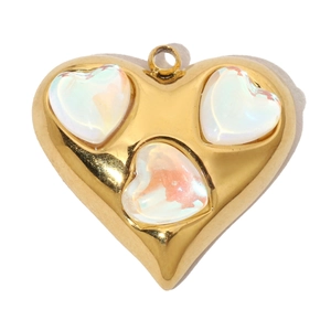 Detailed close-up of a gold heart pendant featuring three colorful white inlaid gemstones
